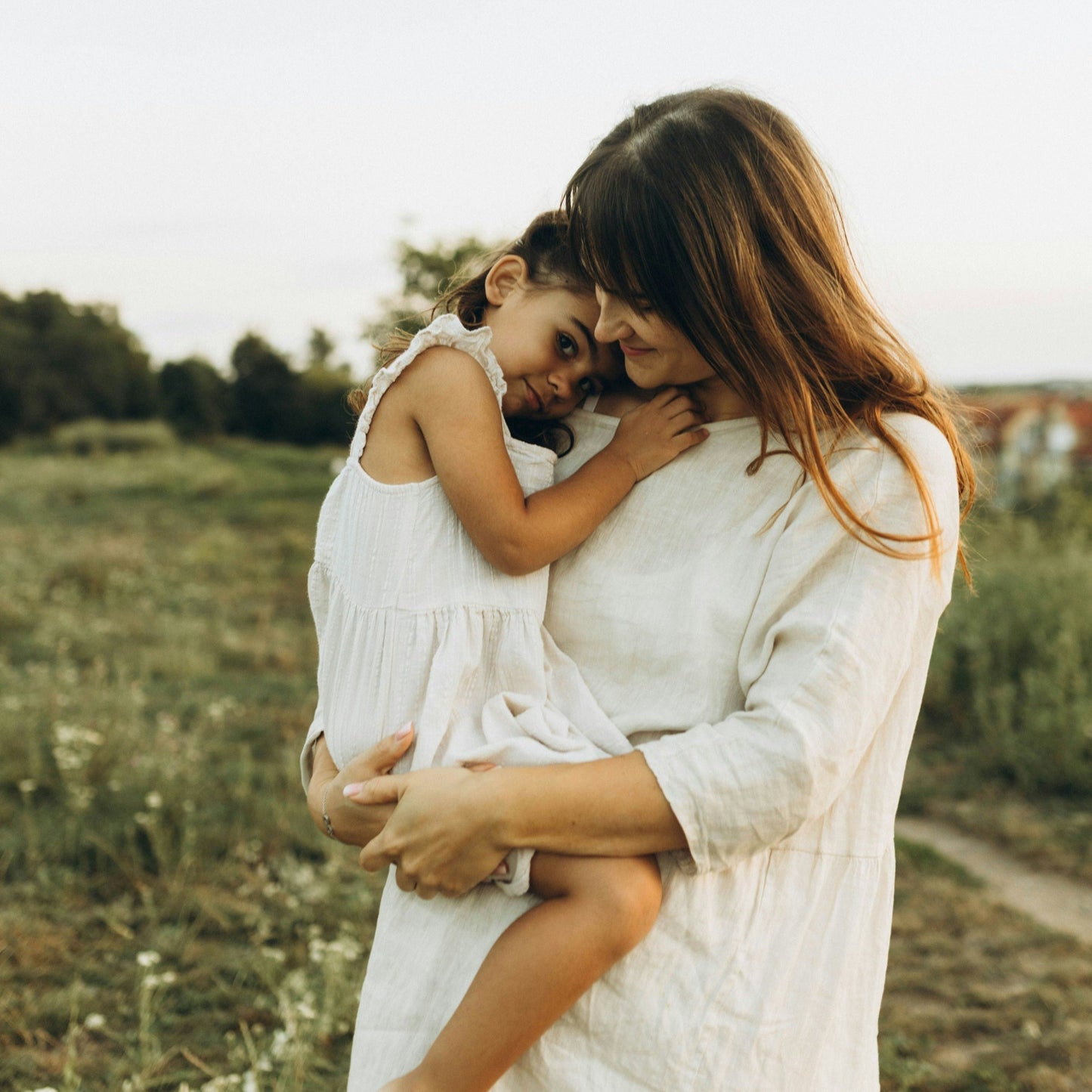 Woman holding a child in a field with a soft focus background
