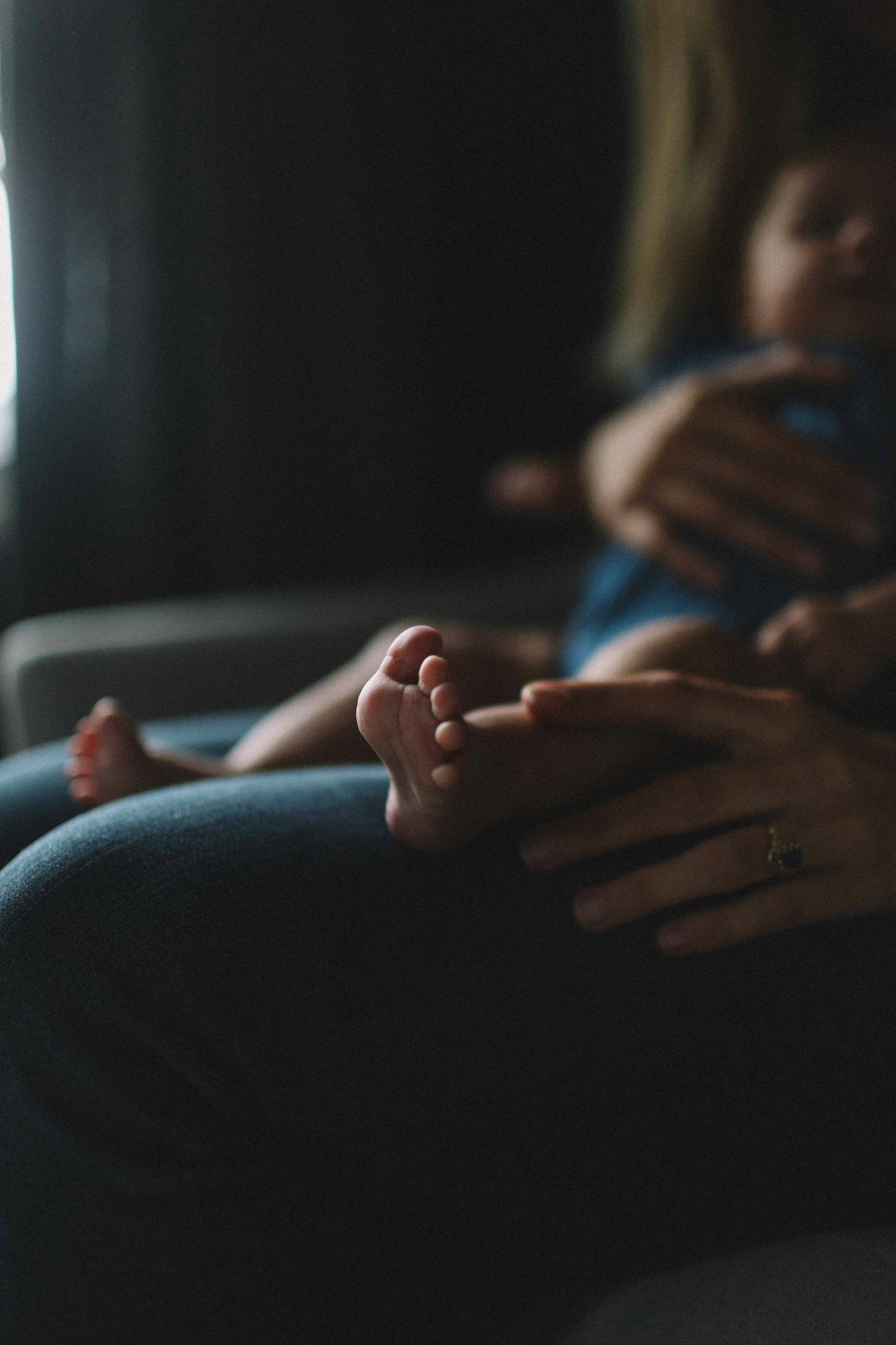 Person holding a baby with their feet into the camera on a blurred background